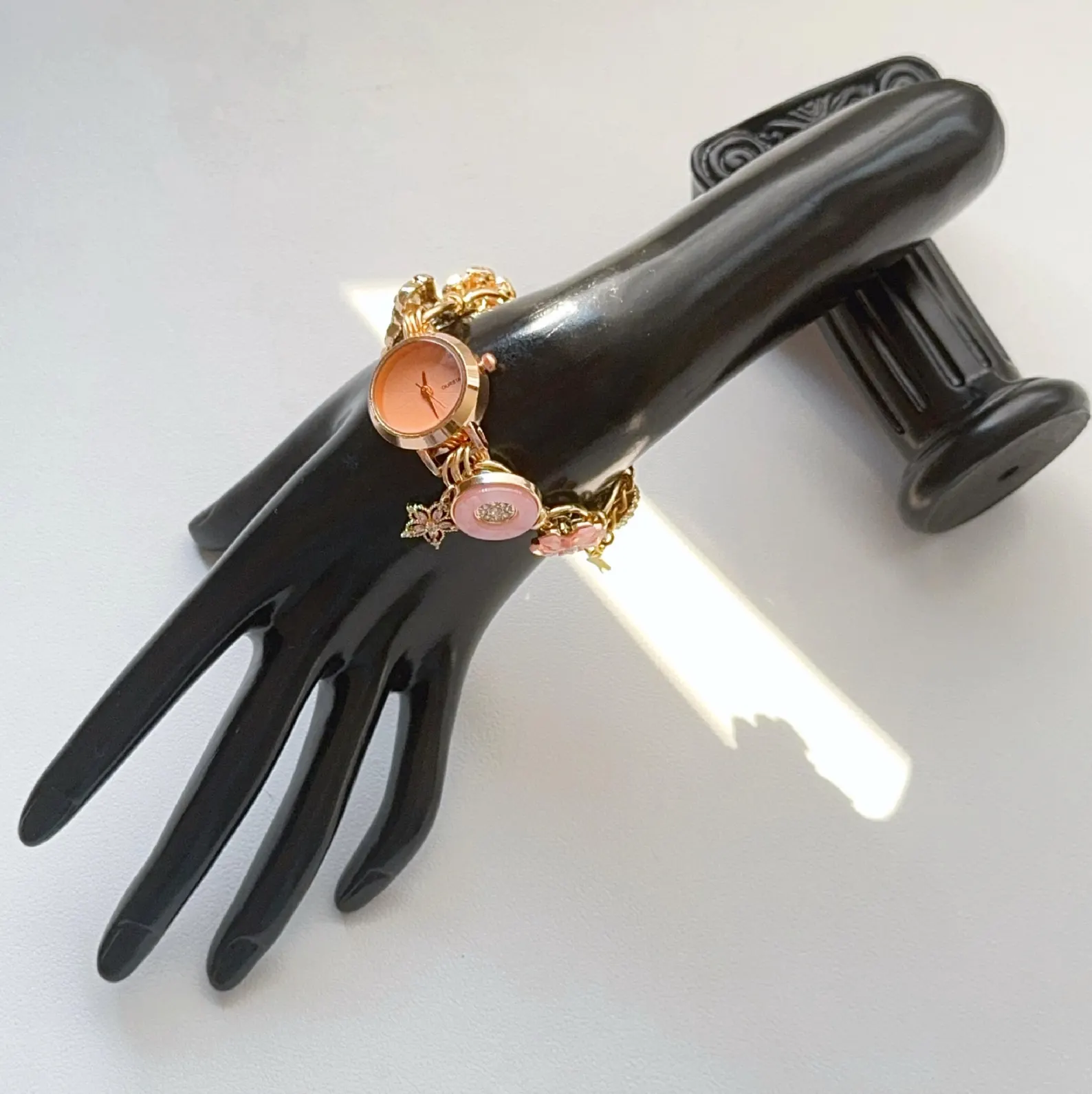 Bold Y2K-style pink bracelet watch with geometric buttons and feminine charms