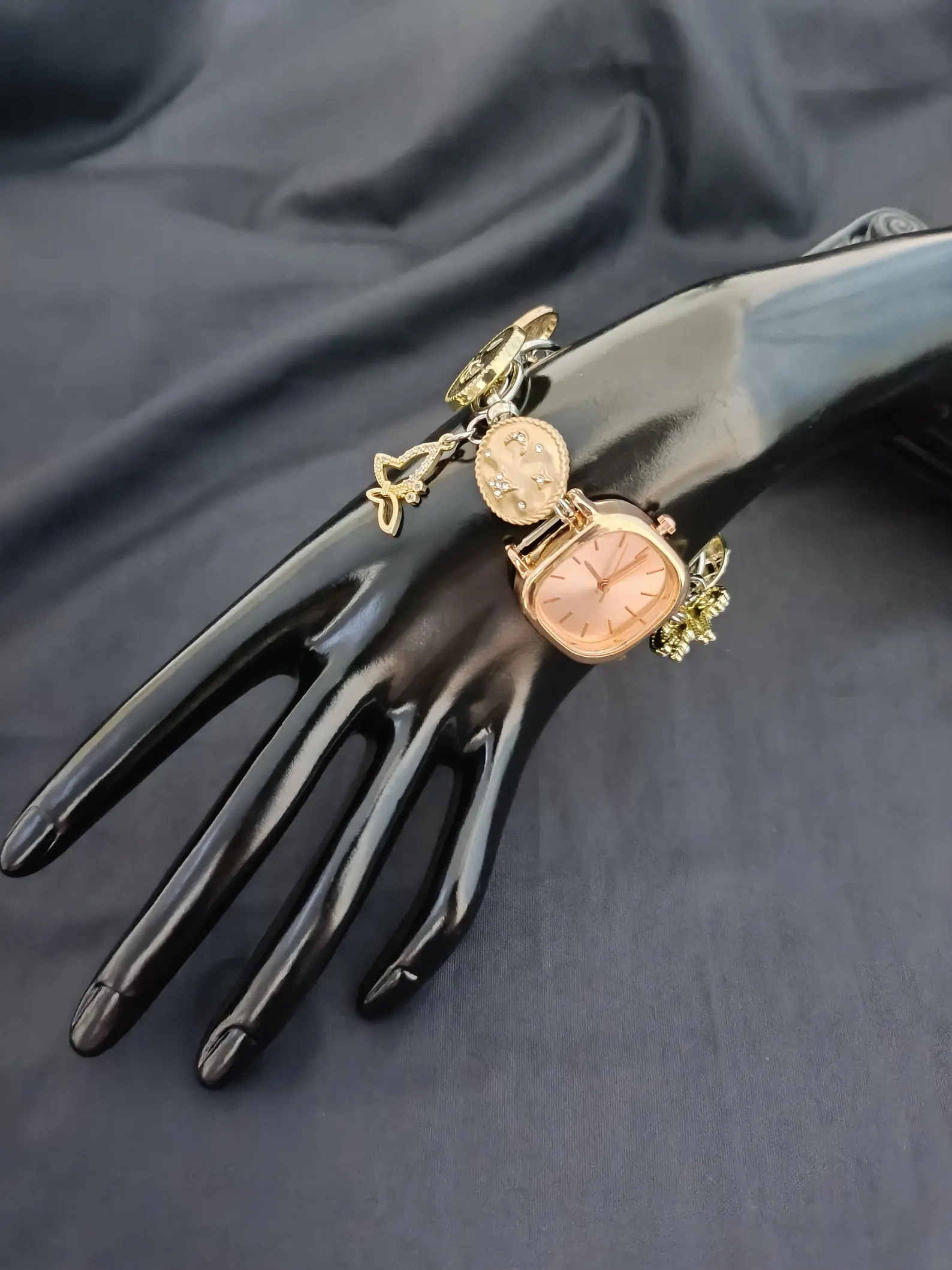 Sleek fashion watch bracelet centered around button clasp system and rotating charm frame