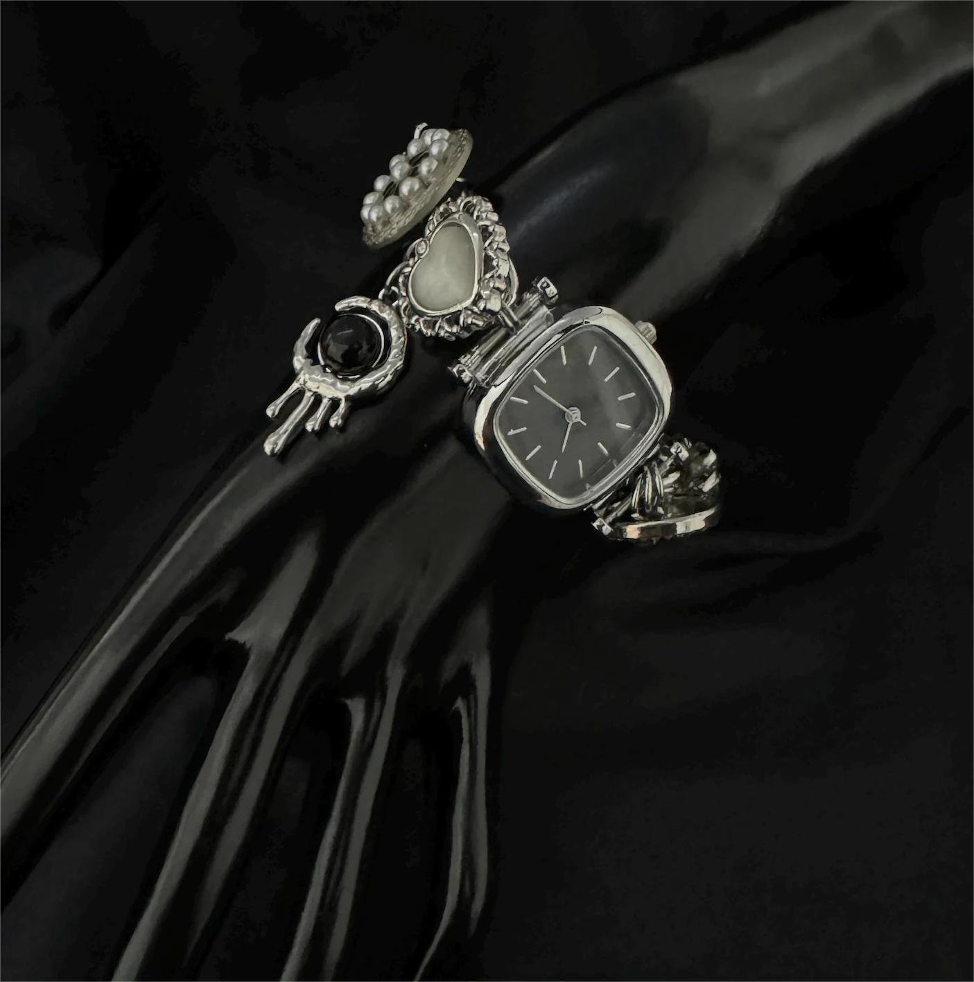 Stainless steel bracelet watch crafted for cyberpunk outfits accented by floating charms and metal buttons