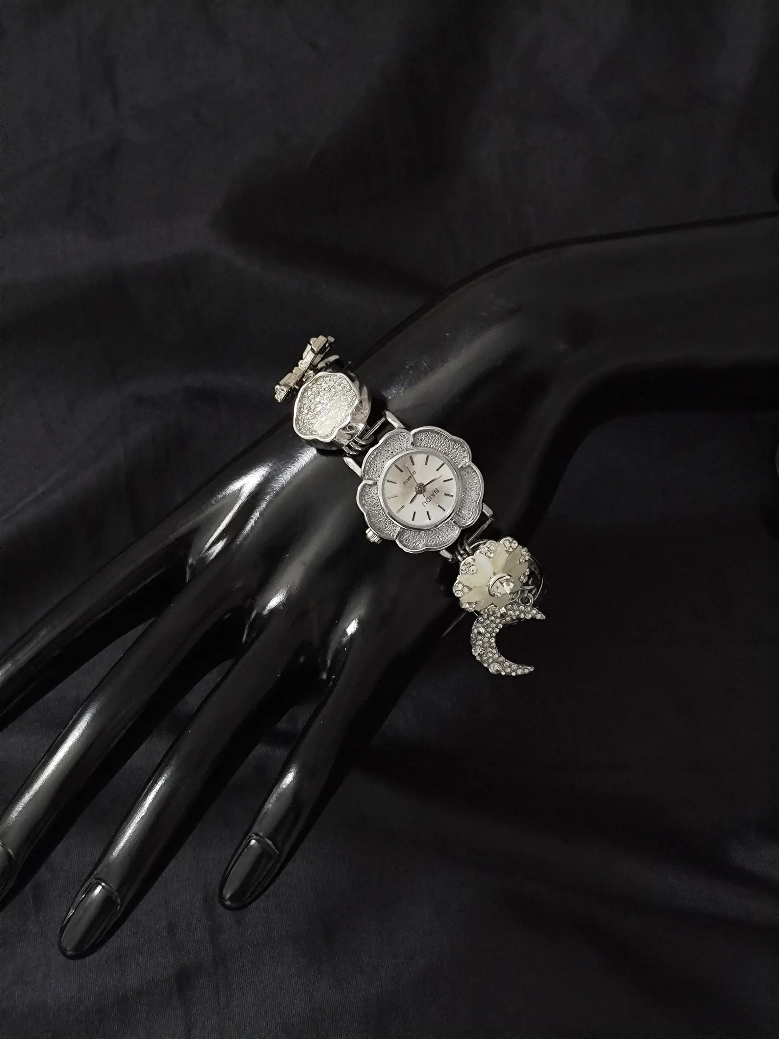 Sculptural watch bracelet using titanium frame, button sensor, and floating charms